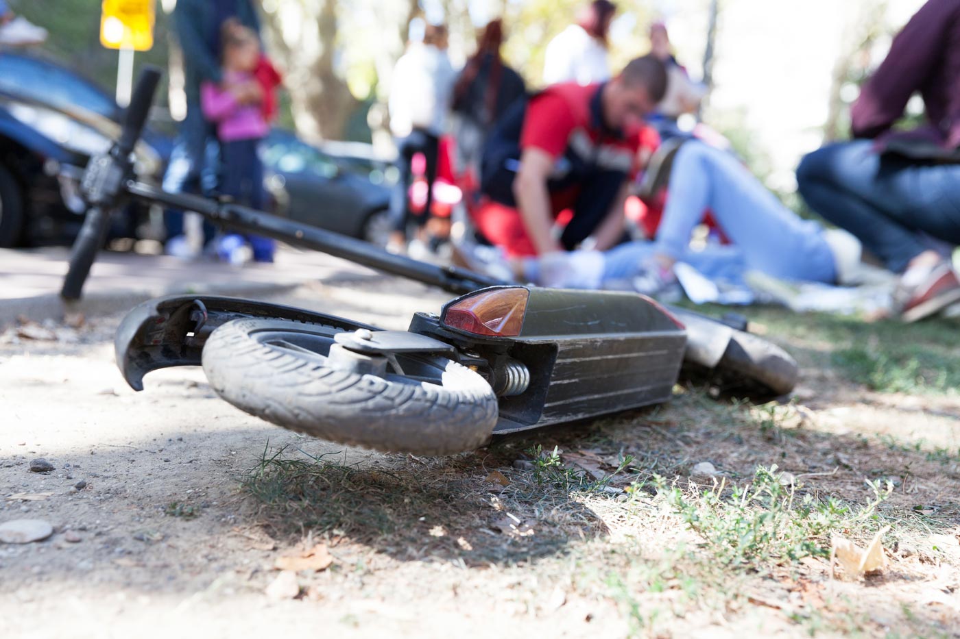 Ein E-Scooter liegt auf der Straße, im Hintergrund wird erste Hilfe geleistet