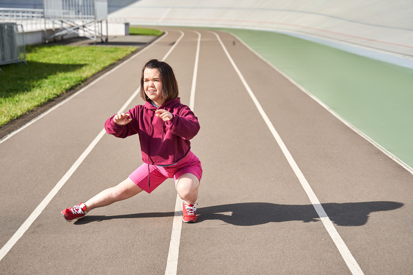 Kleinwüchsige Athletik wärmt sich in einem Stadion auf