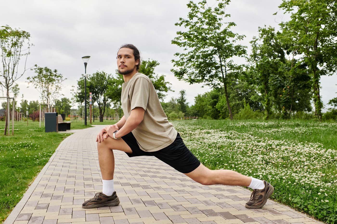 Ein sportlicher, junger Mann dehnt sich in einem Park
