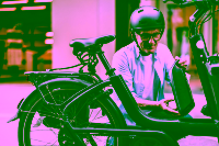 Ein älterer Mann mit Fahrradhelm auf dem Kopf tauscht den Akku an seinem E-Bike aus