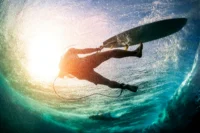Ein Surfer ist ins Wasser gefallen, Blick von unten im Wasser auf den Server und das Surfbrett
